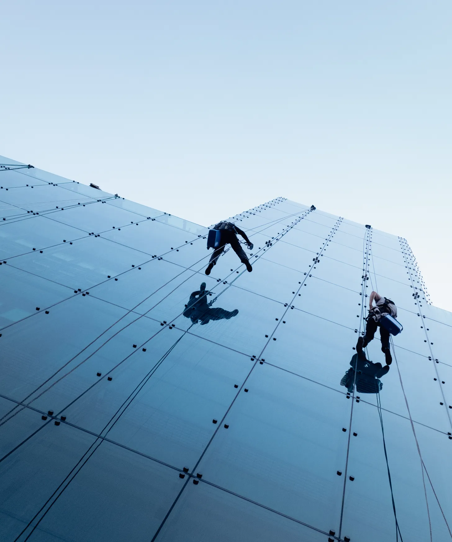 low-angle-shot-two-persons-rappelling-side-tall-building